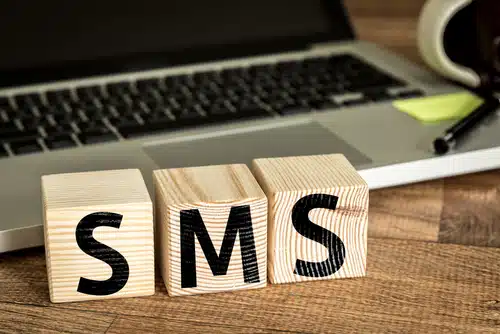 SMS (Short Message Service) written on a wooden cube in a office desk