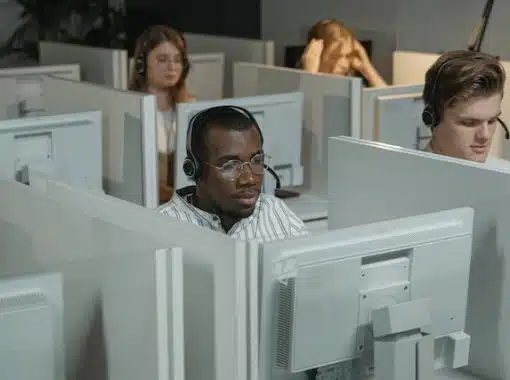 man sitting in cubicle surrounded by monitors