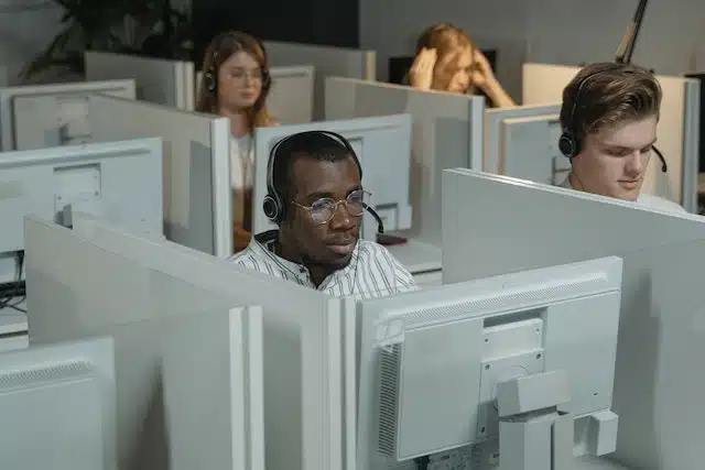 man sitting in cubicle surrounded by monitors