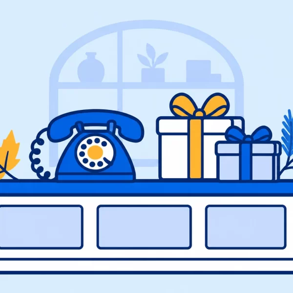 A small business counter with a blue phone, gift boxes, an autumn leaf, and a winter branch.